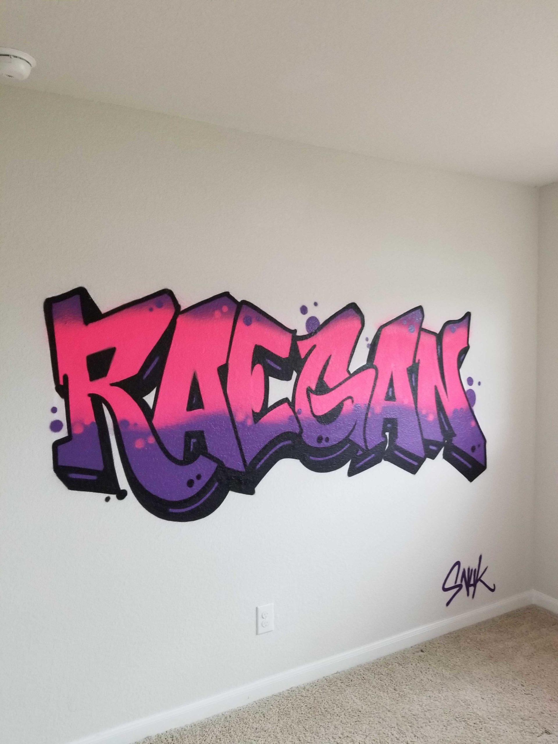 A pink and purple Raegan graffiti mural inside a room