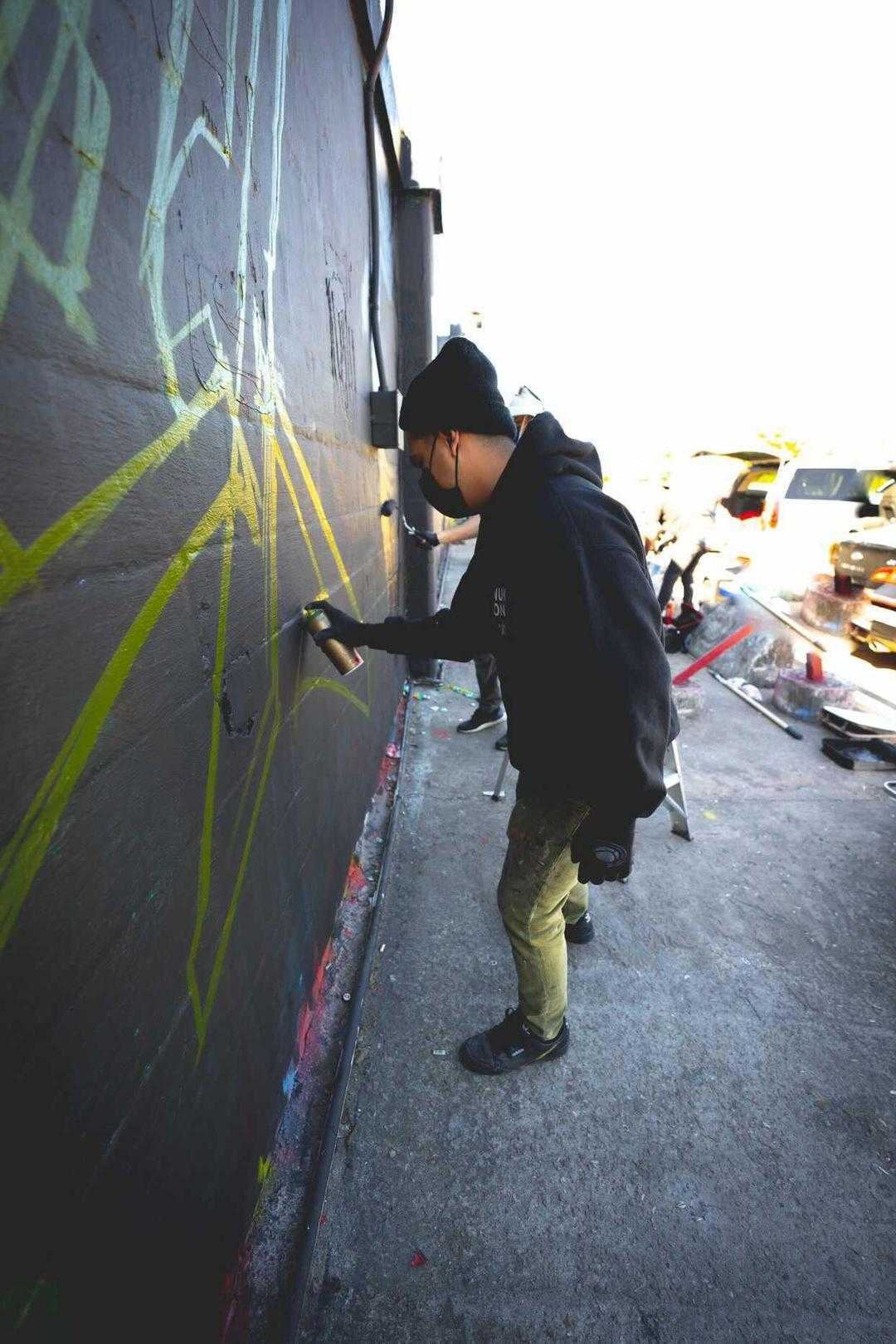Guy spray painting mural on a wall